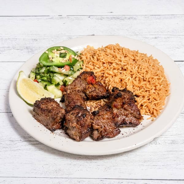 DeAfghanan Cuisine's beef tikka kebab with seasoned rice, fresh salad, and a lime wedge.