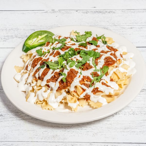 Afghan Aushak, bow-tie pasta topped with meat sauce, garlic yogurt, and cilantro, with a jalapeño.