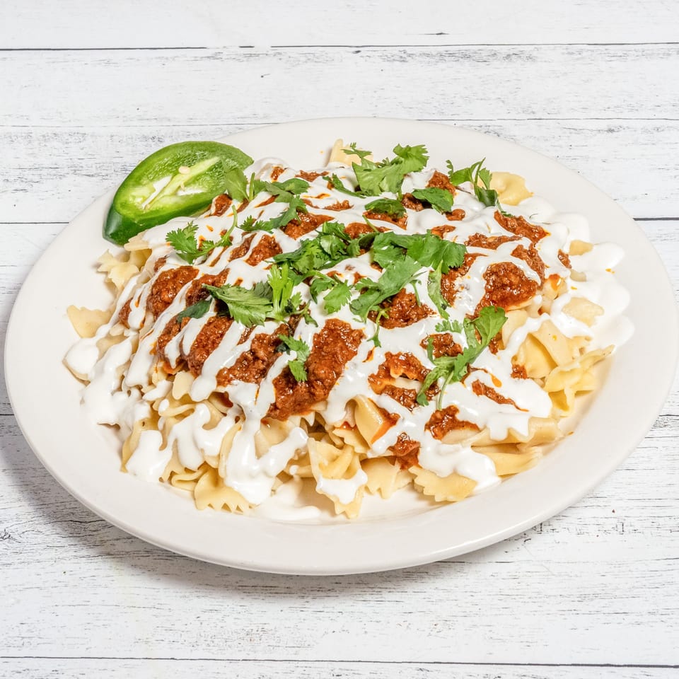 Afghan Aushak, bow-tie pasta topped with meat sauce, garlic yogurt, and cilantro, with a jalapeño.