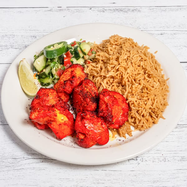 DeAfghanan Cuisine's chicken tikka with rice, salad, and a lime wedge on a white plate.